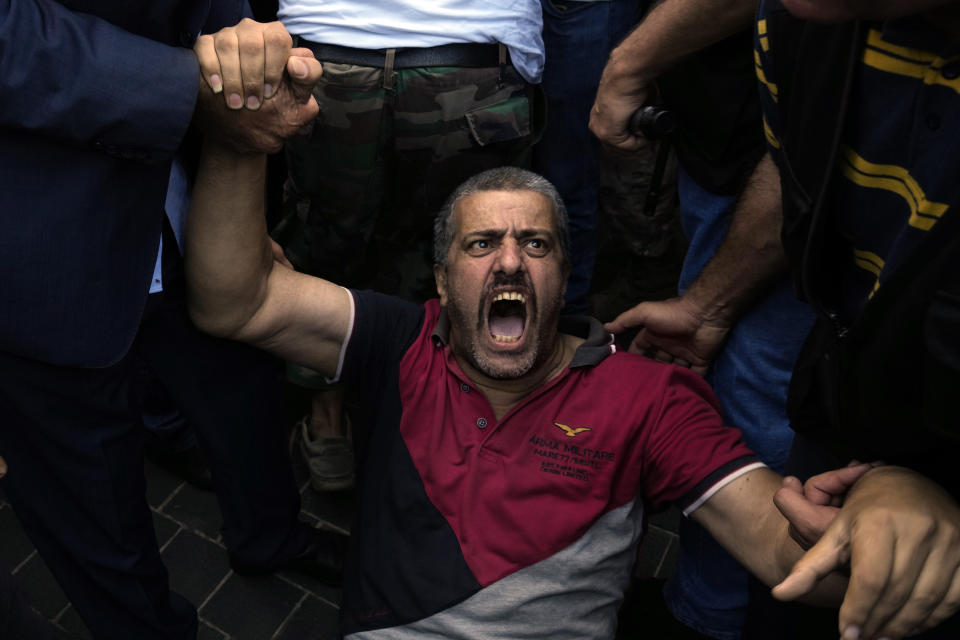 A retired army member lies on the ground and chants slogans as others try to enter to the parliament building while the legislature was in session discussing the 2022 budget in downtown Beirut, Lebanon, Monday, Sept. 26, 2022. The protesters demanded an increase in their monthly retirement pay, decimated during the economic meltdown. (AP Photo/Bilal Hussein)