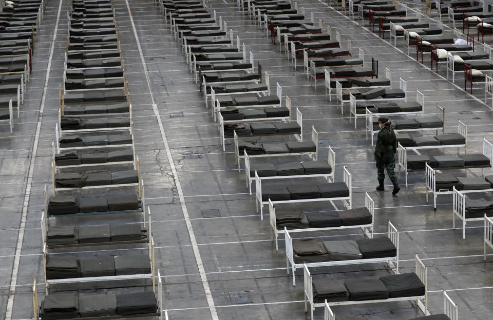 A Serbian soldier inspects beds for treatment of possible COVID-19 infected patients inside of the Belgrade Fair, Serbia, Tuesday, March 24, 2020. For most people, the new coronavirus causes only mild or moderate symptoms. For some it can cause more severe illness. (AP Photo/Darko Vojinovic)