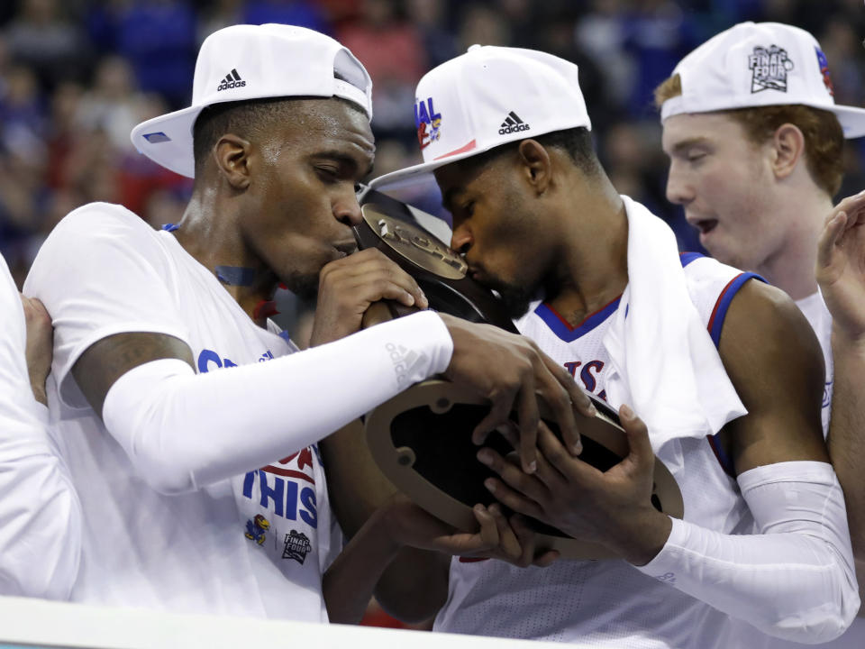 Kansas’ Lagerald Vick, left, and Malik Newman kiss the trophy after defeating Duke 85-81 in overtime a regional final game in the NCAA men’s college basketball tournament Sunday, March 25, 2018, in Omaha, Neb. (AP Photo/Charlie Neibergall)