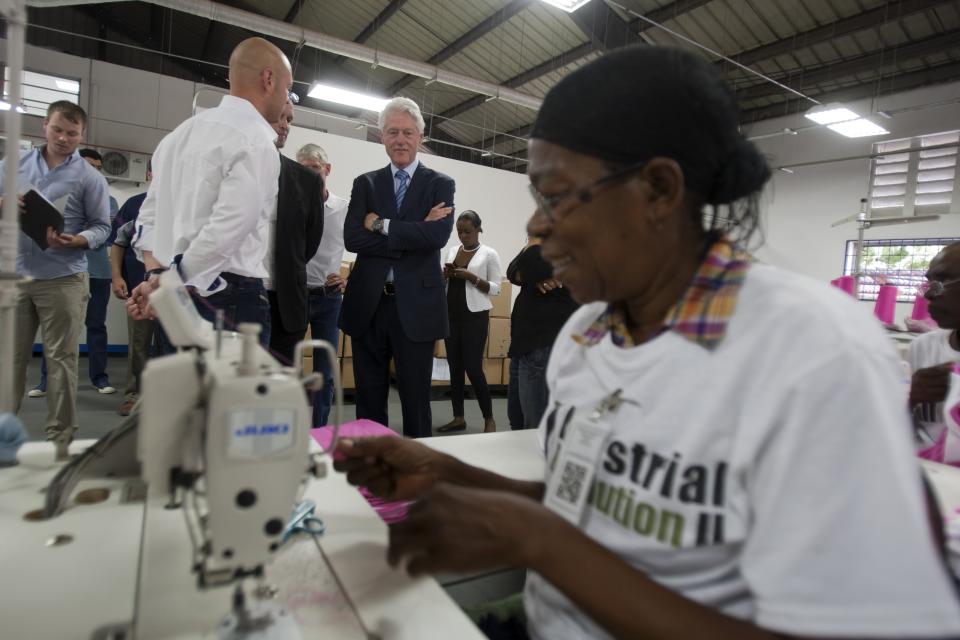 Former U.S. President Bill Clinton observes a worker at the new apparel manufacturer, Industrial Revolution II, S.A. in Port-au-Prince, Haiti, Tuesday Feb. 18, 2014. The manufacturer plans to reinvest half its profits into a health care and education program. Clinton is in a two-day trip to Haiti to visit several projects that focus on agriculture and the environment. (AP Photo/Dieu Nalio Chery)