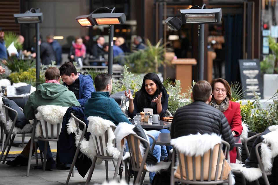 People eat and drink while sitting at tables outside a restaurant at lunchtime in the City of London on April 29, 2021. - Britain has been the European country worst-hit by the virus, recording more than 127,000 deaths, although it rolled out a succesful mass-vaccination campaign in early December, using AstraZeneca, Pfizer/BioNTech and Moderna vaccines. (Photo by DANIEL LEAL-OLIVAS / AFP) (Photo by DANIEL LEAL-OLIVAS/AFP via Getty Images)