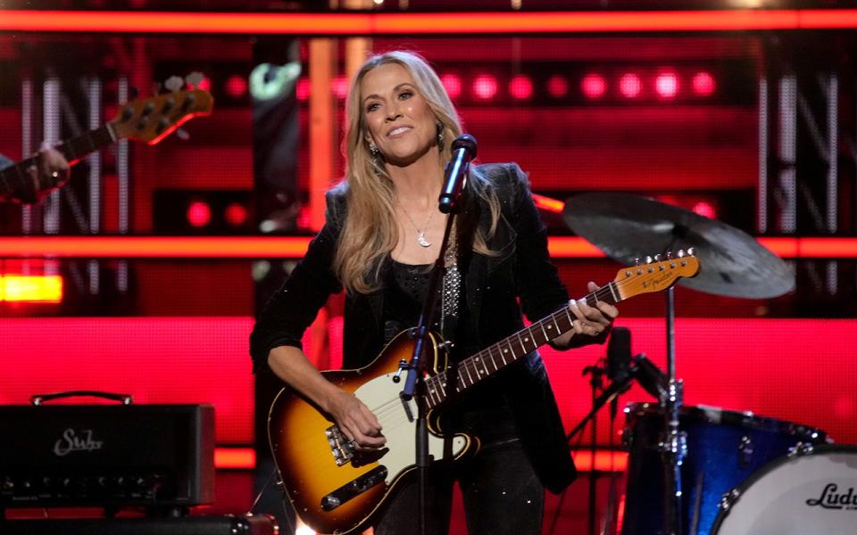 Sheryl Crow performing on stage with guitar