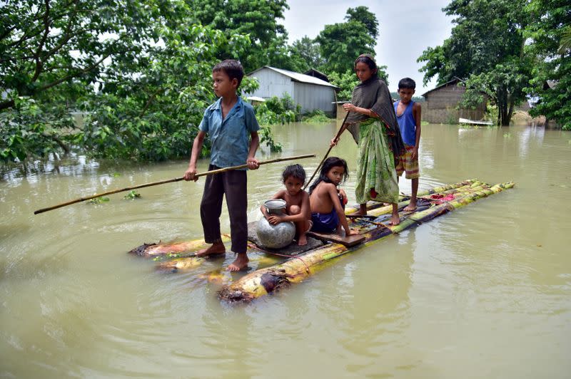 FILE PHOTO: Villagers row a makeshift raft through a flooded field to reach a safer place at the flood-affected Mayong village
