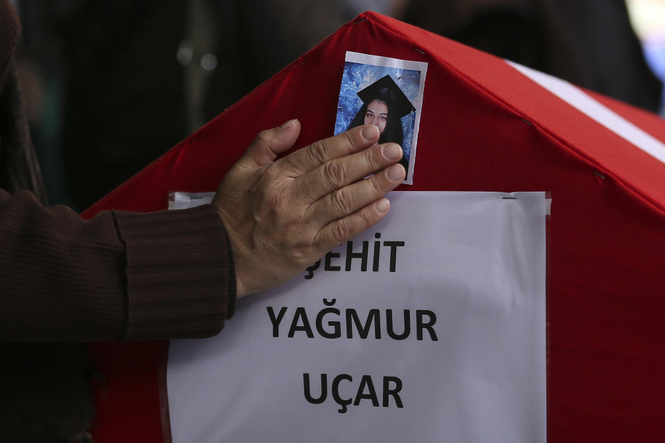 A person poses his hand on a photo of Yagmur Ucar, the 15-year-old daughter of Arzu Ozsoy, both of them dead in Sunday's explosion occurred on Istiklal avenue, during their funeral in Istanbul, Turkey, Monday, Nov. 14, 2022. Turkish police said Monday that they have detained a Syrian woman with suspected links to Kurdish militants and that she confessed to planting a bomb that exploded on a bustling pedestrian avenue in Istanbul, killing six people and wounding several dozen others. (AP Photo/Emrah Gurel)