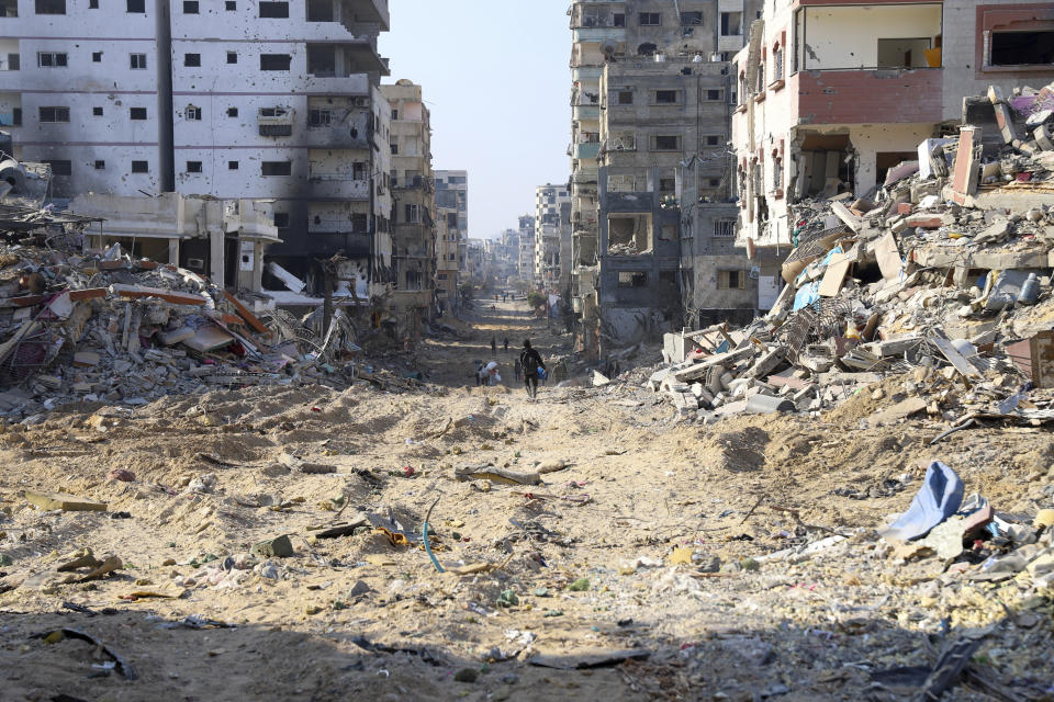 Palestinians walk between the remains of destroyed buildings following the Israeli bombardment on the main road of Gaza City on Tuesday, Jan. 2, 2024. (AP Photo/Mohammed Hajjar)