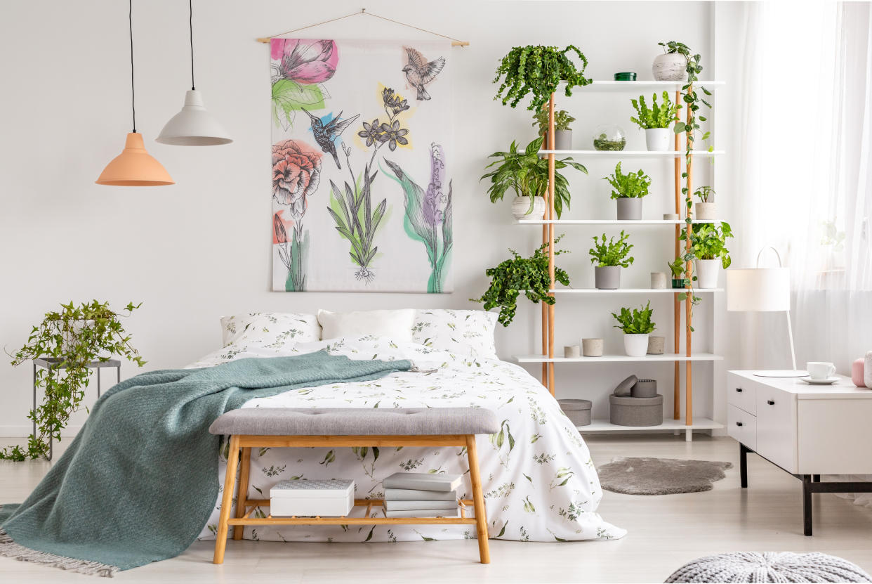  Bright airy small bedroom with low bed natural lighting and lots of green plants and clever storage shelves and ottomans Getty - KatarzynaBialasiewicz. 