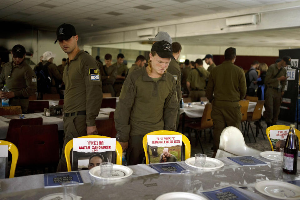 Israeli soldiers look at chairs for hostages held in Gaza at a Passover seder table on Thursday, April 11, 2024, at the communal dining hall at Kibbutz Nir Oz in southern Israel, where a quarter of all residents were killed or captured by Hamas on Oct. 7, 2023. (AP Photo/Maya Alleruzzo)