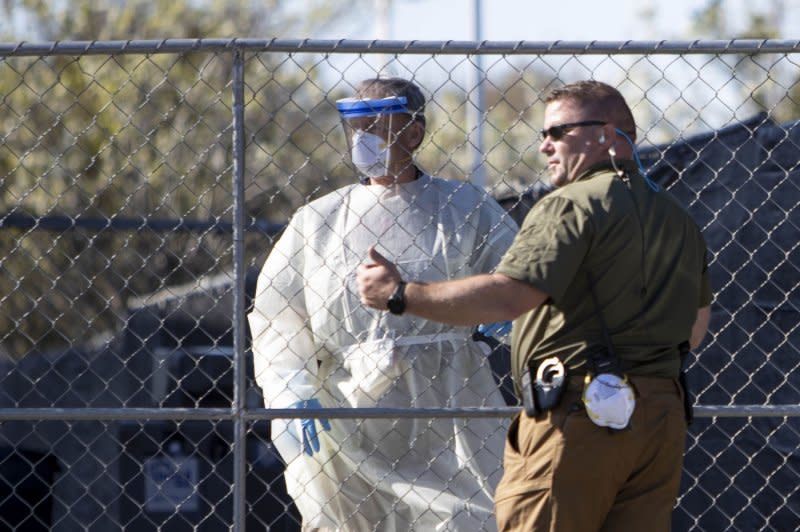 An unidentified health worker chats with a U.S. Marshal guarding a Fairfield Inn, a hotel purchased by the state of California to be used as a quarantine facility for COVID-19 patients in San Carlos, Calif., on March 12, 2020. On February 6, 2020, the earliest known death from the novel coronavirus took place in Santa Clara County, Calif. File Photo by Peter DaSilva/UPI