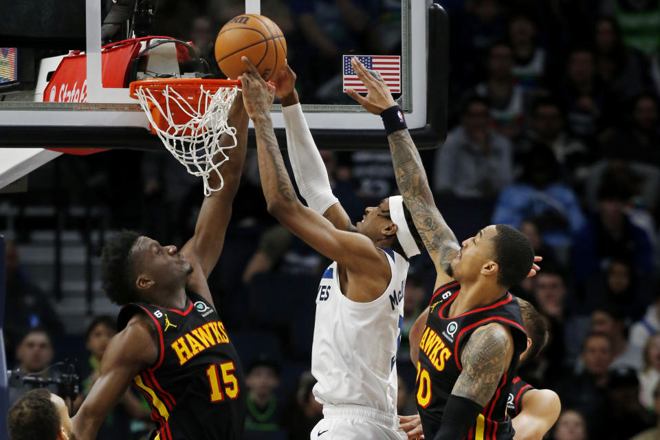 Minnesota Timberwolves forward Jaden McDaniels, in white, goes to the basket between Atlanta Hawks center Clint Capela (15) and forward John Collins (20) in the fourth quarter of an NBA basketball game Wednesday, March 22, 2023, in Minneapolis. The Timberwolves won 125-124. (AP Photo/Bruce Kluckhohn)