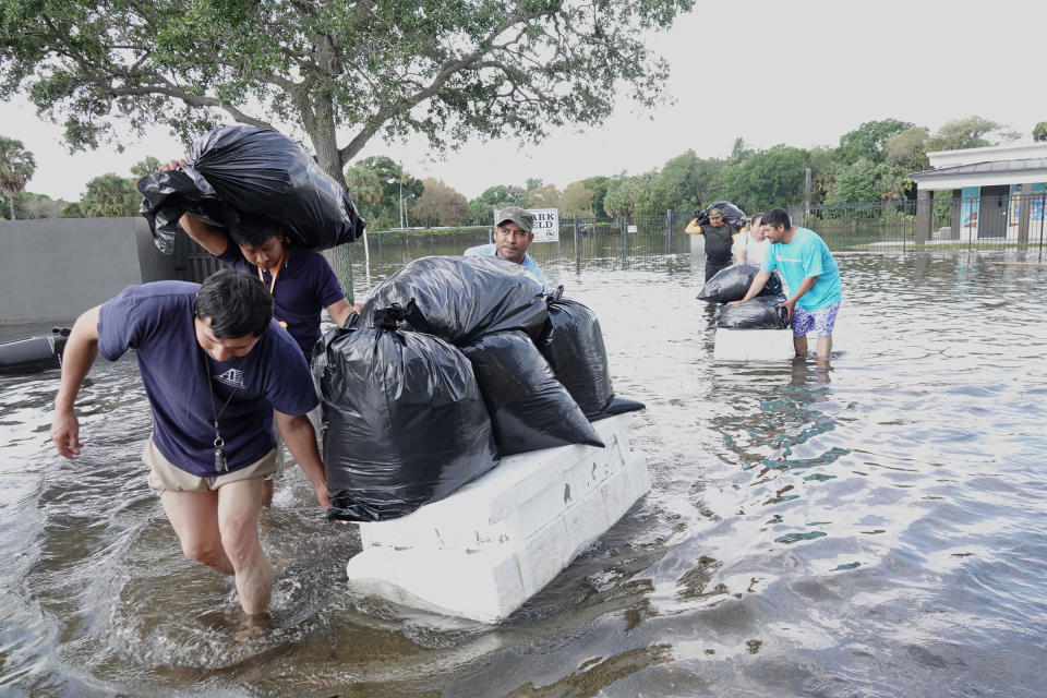 People try to save valuables as they wade through flood waters in the Edgewood neighborhood of Fort Lauderdale, Fla., on April 13, 2023.<span class="copyright">Joe Cavaretta—South Florida Sun Sentinel/Tribune News Service/Getty Images</span>