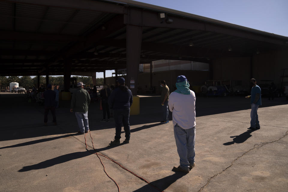 Hispanic farm workers wait in line to receive the Pfizer-BioNTech COVID-19 vaccine in Mecca, Calif., Thursday, Jan. 21, 2021. The farmworkers who got their shots are among the millions of immigrants around the United States, who advocacy groups warn may be some of the most difficult people to reach during the largest vaccination campaign in American history. (AP Photo/Jae C. Hong)