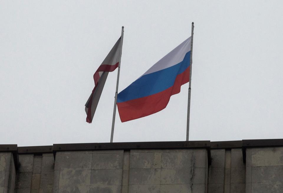 A Russian flag is raised next to a Crimean flag on top of the Crimean parliament building in Simferopol