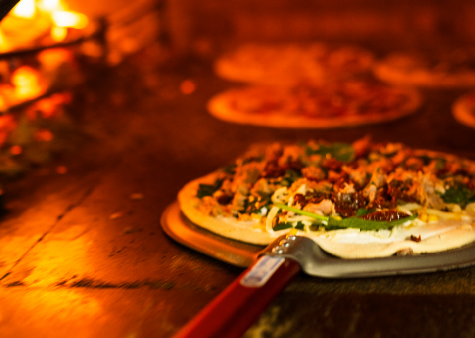 Sausage pizza being pulled out of the oven.