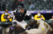 San Diego Padres' Tommy Pham, front, avoids the tag by Colorado Rockies catcher Dom Nunez to score on a ground ball by Ha-Seong Kim during the sixth inning of a baseball game Tuesday, May 11, 2021, in Denver. (AP Photo/David Zalubowski)