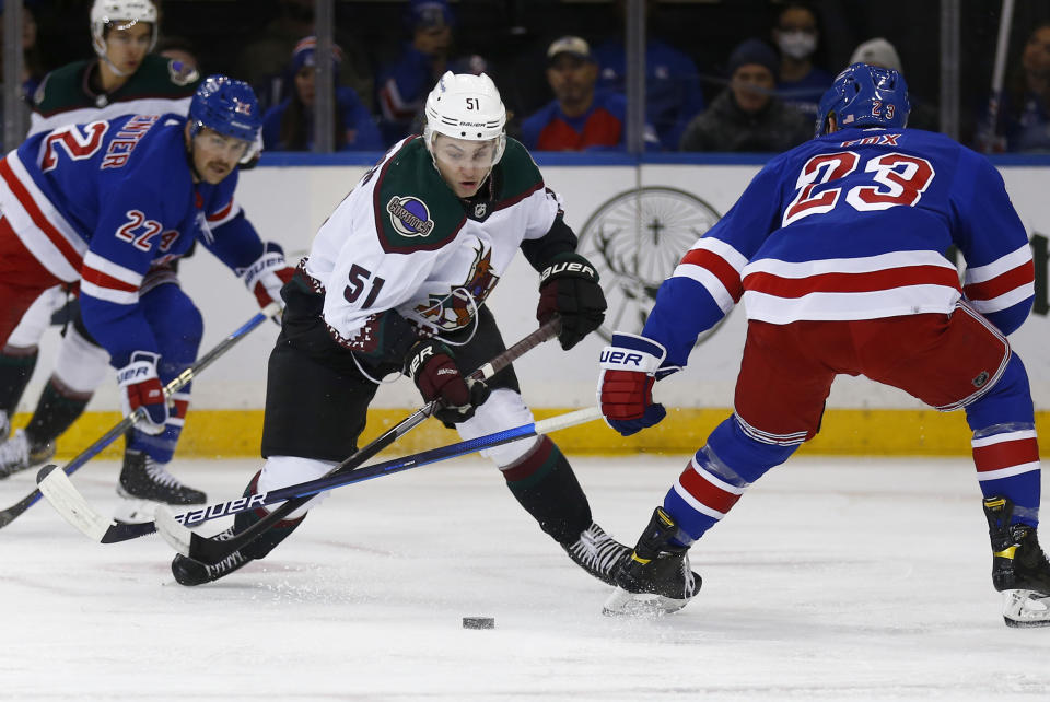 Arizona Coyotes Troy Stecher (51) skates with the puck between New York Rangers center Ryan Carpenter (22) and defenseman Adam Fox (23) during the second period of an NHL hockey game Sunday, Nov. 13, 2022, in New York. (AP Photo/John Munson)