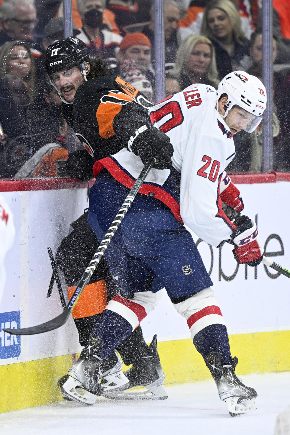 Philadelphia Flyers' Zack MacEwen, left, is checked into the boards by Washington Capitals' Lars Eller during the second period of an NHL hockey game, Saturday, Feb. 26, 2022, in Philadelphia. (AP Photo/Derik Hamilton)