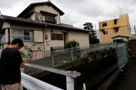 A mourner prays for the victims of the arson attack in front of the torched Kyoto Animation building n Kyoto