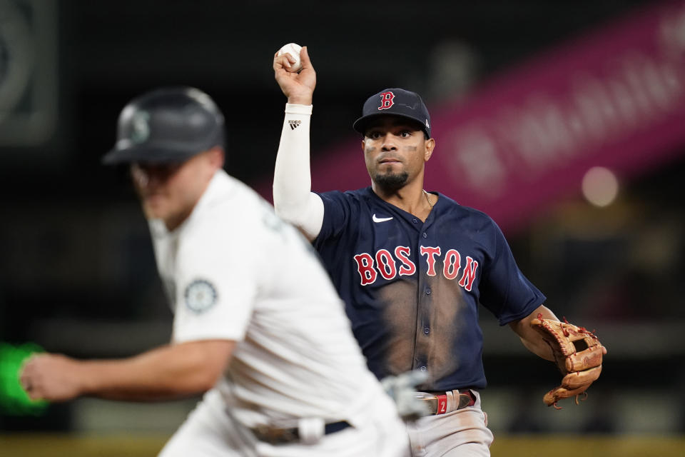 Boston Red Sox shortstop Xander Bogaerts, right, readies a toss to first base as Seattle Mariners' Kyle Seager is caught in a rundown between first and second during the eighth inning of a baseball game Tuesday, Sept. 14, 2021, in Seattle. Seager was tagged out on the play. (AP Photo/Elaine Thompson)