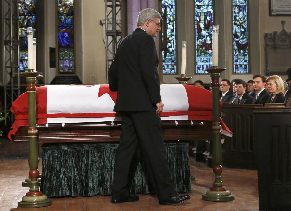 Canada's Prime Minister Stephen Harper lays a hand on the casket of former finance minister Jim Flaherty after speaking at his state funeral in Toronto, April 16, 2014.