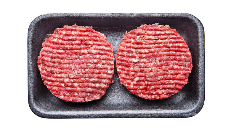 Raw burger patties in tray