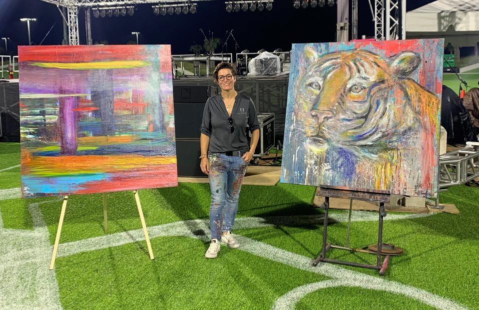 Fort Myers artist Lacy McClary poses with two of her paintings. She's working with artist Summer DeSalvo to paint murals on a three-story elevator shaft in Fort Myers Beach's Times Square area. The shaft's surrounding building was destroyed by Hurricane Ian.