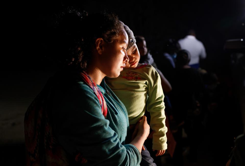 Immigrants stand near the bank of the Rio Grande after crossing the river from Mexico on April 27, 2021, in Roma, Texas.