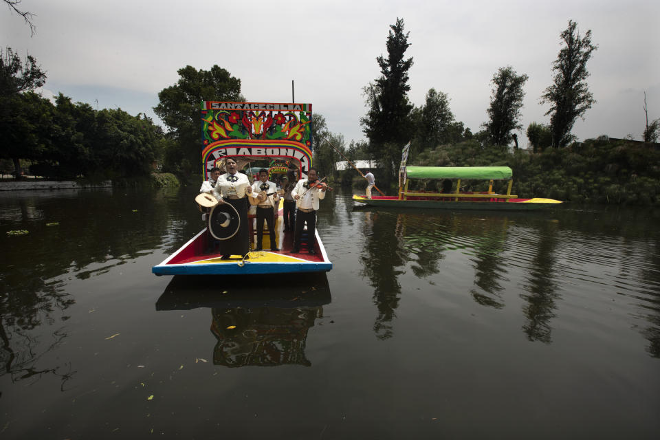 Mariachis perform on one of the painted wooden boats, known as a trajinera, popular with tourists that ply the water canals in the Xochimilco district of Mexico City, after all activities had been on pause for the past six months due to the COVID-19 pandemic. (AP Photo/Marco Ugarte)