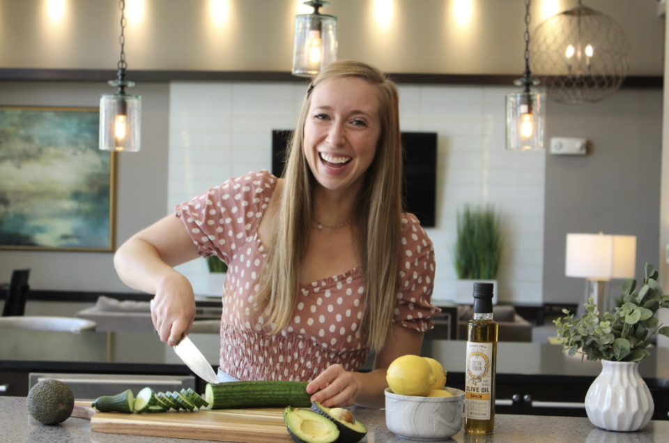 Kate preparing food with a cucumber, avocado, lemons, and olive oil on the counter