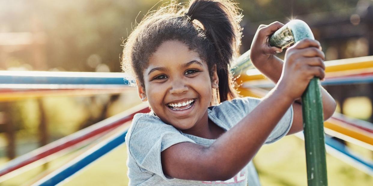 a girl smiling at camera playing on playground carousel - teaching kids to stand up for themselves