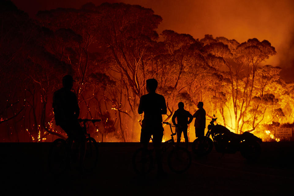 LAKE TABOURIE, AUSTRALIA - JANUARY 04: Residents look on as flames burn through bush on January 04, 2020 in Lake Tabourie, Australia. A state of emergency has been declared across NSW with dangerous fire conditions forecast for Saturday, as more than 140 bushfires continue to burn. There have been eight confirmed deaths in NSW since Monday 30 December. 1365 homes have been lost, while 3.6 million hectares have been burnt this fire season. (Photo by Brett Hemmings/Getty Images)