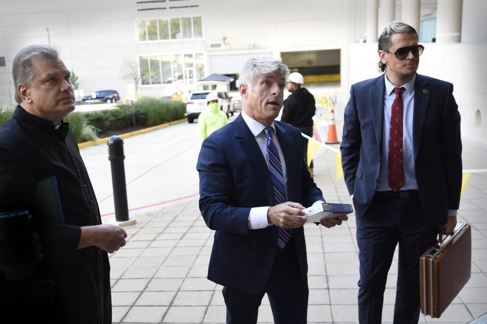 Fr. Paul Kalchik, left,St. Michael's founder and CEO Michael Voris, center, and Milo Yiannopoulos talk with a court officer before entering the federal courthouse, Thursday, Sept. 30, 2021, in Baltimore. U.S. District Judge Ellen Hollander scheduled a hearing Thursday for the lawsuit that rally planners St. Michael’s Media filed against the city. St. Michael's claims city officials cancelled the Nov. 16 rally because they disapprove of the group's religious message. (AP Photo/Gail Burton)