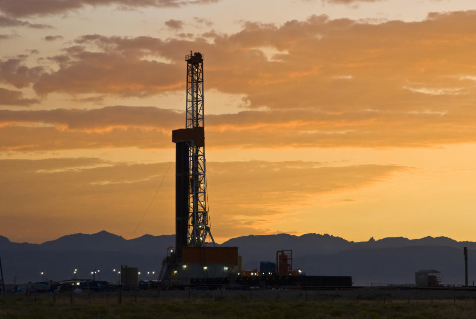 A drilling rig in Wyoming with a sunset in the background.