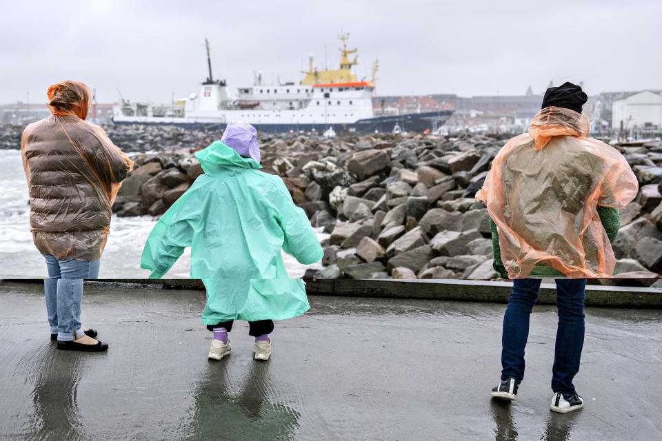 People stand in windy weather on the outer pier at Hirtshals Harbour, Denmark, Monday, Aug. 7, 2023. Stormy weather across northern Europe has caused airport delays, suspended ferry service and a train’s partial derailment. (Henning Bagger/Ritzau Scanpix via AP)
