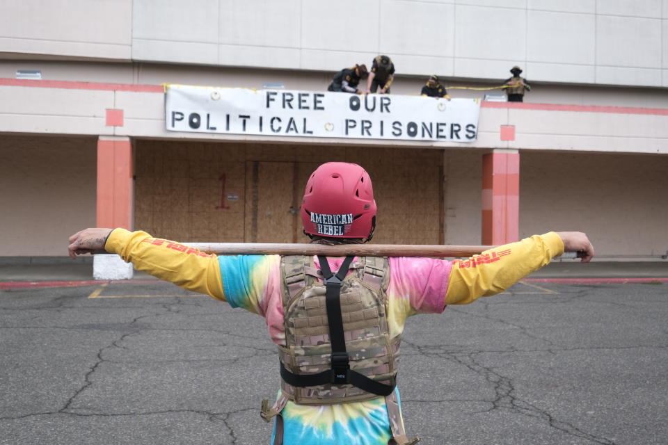 Members of the far-right group Proud Boys unfurl a banner at a rally in an abandoned parking lot on the outskirts of town on Sunday, Aug. 22, 2021, in Portland, Ore. (AP Photo/Alex Milan Tracy)