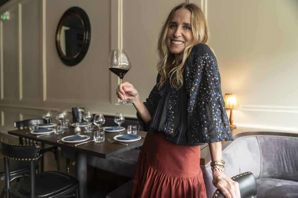 In this Saturday, June 19, 2021, photo, Caroline Styne, owner and wine director at The Lucques Group, smiles with a glass of wine at the A.O.C. Brentwood restaurant in Los Angeles. Styne has turned away dozens of customers at the company's A.O.C. West Hollywood restaurant because she doesn't have the staff to serve them, leaving seats empty. (AP Photo/Damian Dovarganes)