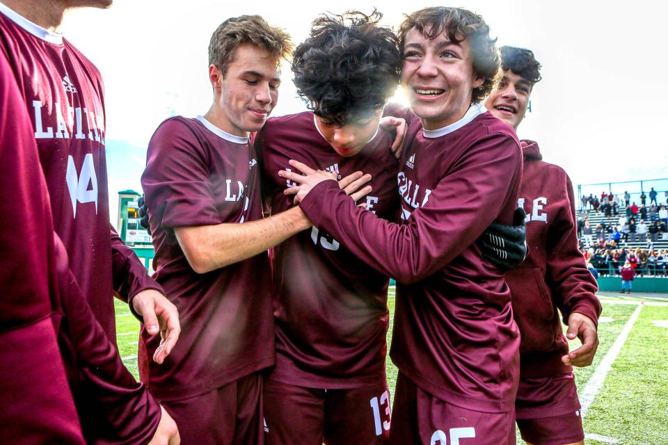 An emotional Moises Morales is greeted by Ethan Morris, left, and Garrett Clare at the center of the field during La Salle's postgame celebration.