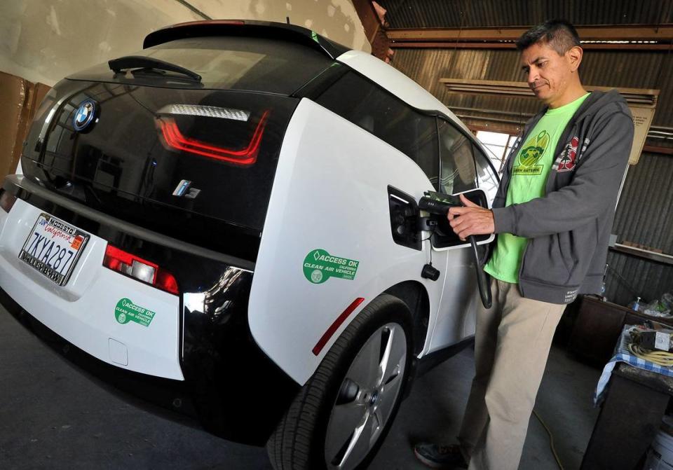 Reyes Barboza Jr. charges a BMW electric car, part of the Green Raiteros electric vehicle ride share program, in 2018.