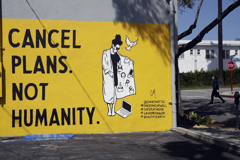 A sign reads "Cancel Plans Not Humanity" Tuesday, April 14, 2020, in Los Angeles. Murals with themes centered around the coronavirus have been popping up on the walls of businesses in the California city. California Gov. Gavin Newsom on Tuesday unveiled an outline for what it will take to lift coronavirus restrictions in the nation's most populous state, asking more questions than answering them as he seeks to temper the expectations of a restless, isolating public. (AP Photo/Marcio Jose Sanchez)