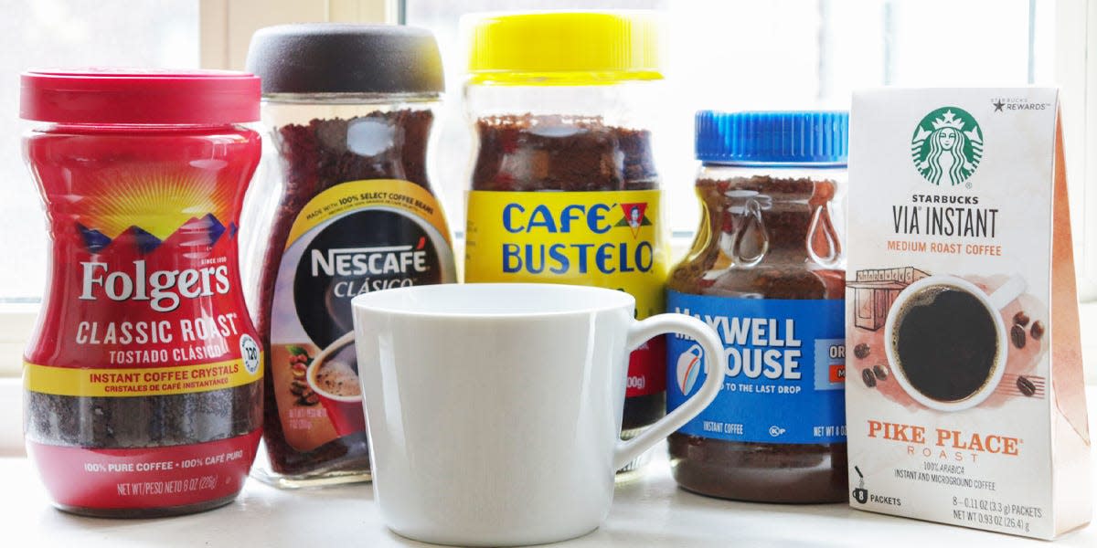 five instant coffees lined up with a white mug in front