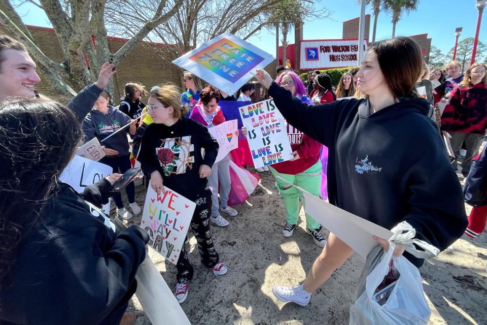 Fort Walton Beach High School student Lauren Sprenkle hands out signs during a rally after school Monday to protest the recent Florida legislation dubbed the "Don't Say Gay" bill.