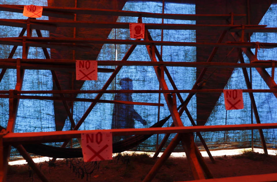 A circus performer is silhouetted on the canvass of the Jumbo Circus tent, as signs for social distancing hang from the bleachers inside the tent as the circus enters its fourth month closed due to the COVID-19 lockdown in El Alto, Bolivia, Monday, June 15, 2020. Before the lockdown, the circus held one daily performance on weekdays and twice a day on weekends. (AP Photo/Juan Karita)