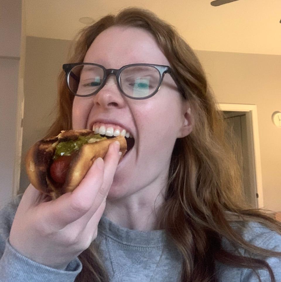 A woman eating a hotdog with verve and gusto.