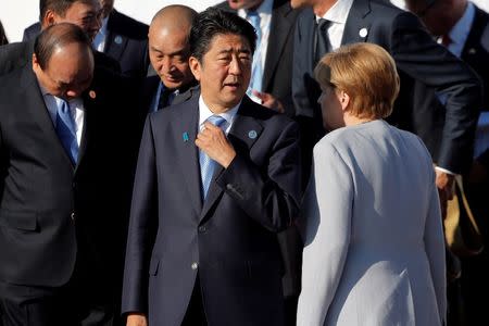 German Chancellor Angela Merkel walks behind Japan's Prime Minister Shinzo Abe as leaders arrive for a family photo during the Asia-Europe Meeting (ASEM) summit just outside Ulaanbaatar, Mongolia, July 16, 2016. REUTERS/Damir Sagolj