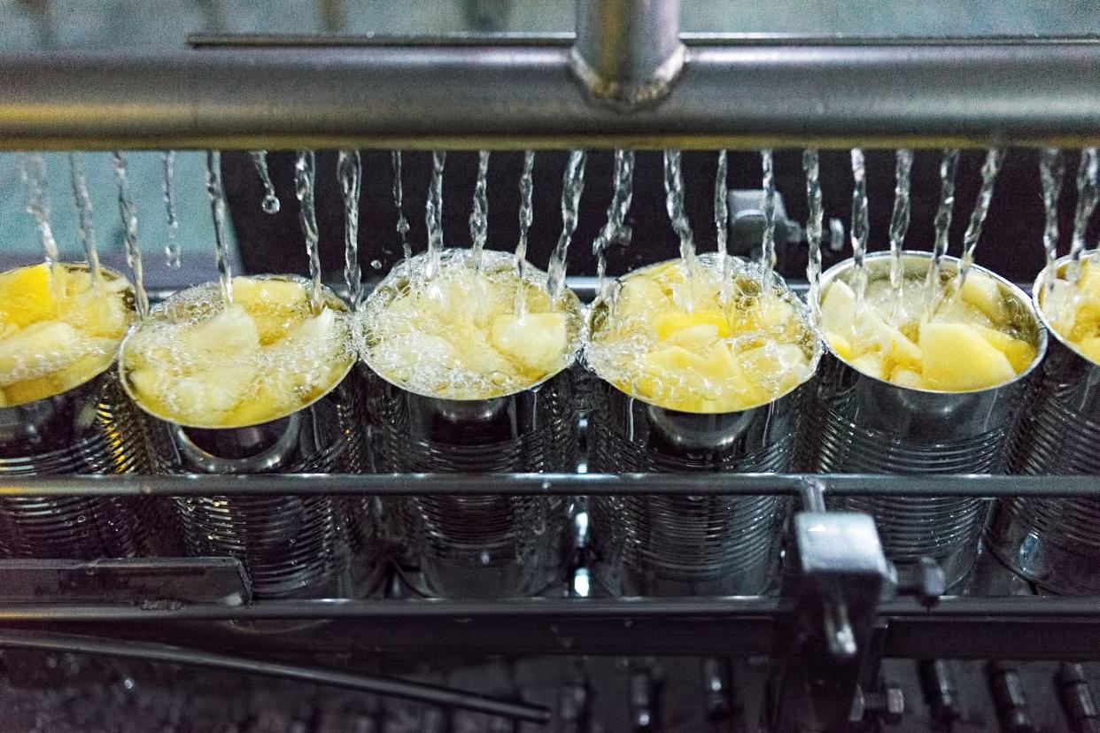 canned foods being made in factory, adding water to cans