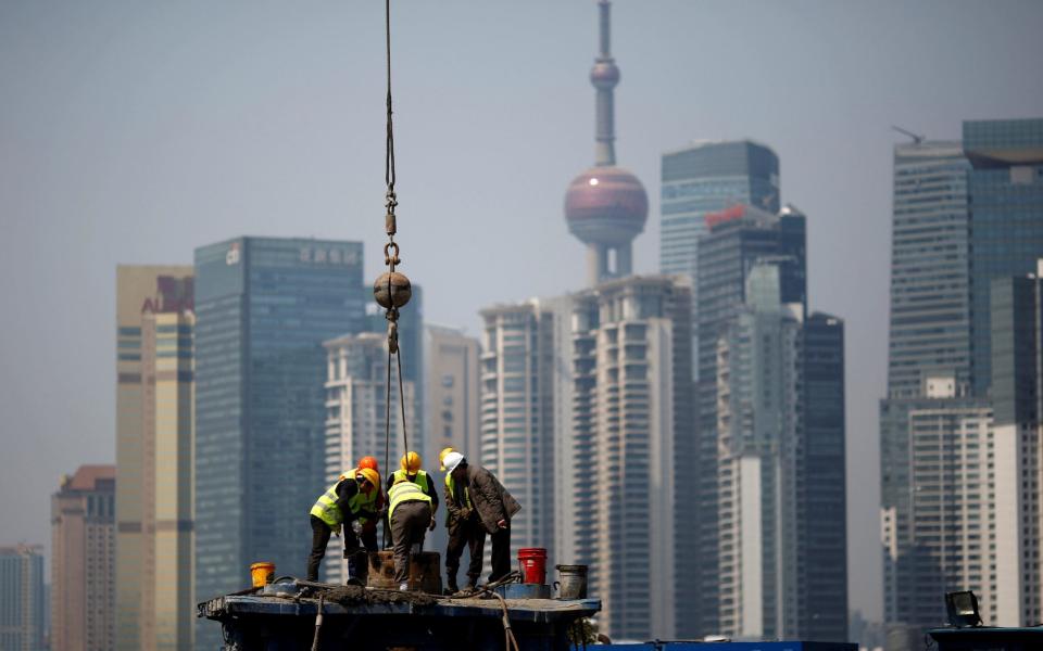 Workers work at a construction site in front of Shanghai's financial district of Pudong in Shanghai - REUTERS