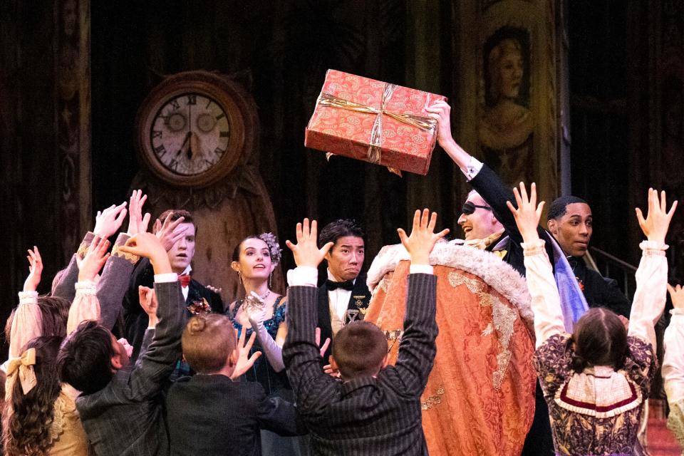 Herr Drosselmeyer, played by Austin Powers, wearing an eyepatch, gives out a gift to party children during a preview rehearsal for BalletMet’s performance of "The Nutcracker" at the Ohio Theatre.