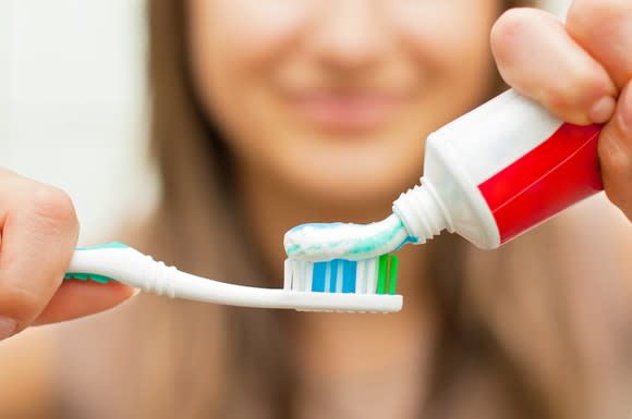 A woman puts toothpaste on a toothbrush.