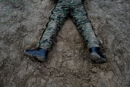 A recruit lies on the ground during his 16-day basic training for Poland's Territorial Defence Forces, at a shooting range near Siedlce, Poland, December 7, 2017. REUTERS/Kacper Pempel/Files