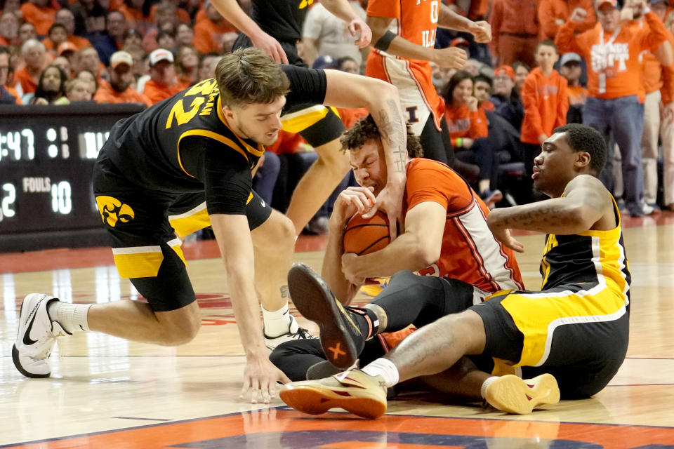Iowa's Owen Freeman (32) battles Illinois' Coleman Hawkins for the ball as Tony Perkins watches during the second half of an NCAA college basketball game Saturday, Feb. 24, 2024, in Champaign, Ill. Illinois won 95-85. (AP Photo/Charles Rex Arbogast)