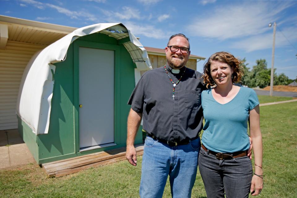 The Rev. Bo Ireland, leader of the Lazarus Community at Clark United Methodist Church, poses for a photo with his wife Alanna in front of a model of one of the structures that will be used for transitional housing for people experiencing homelessness.